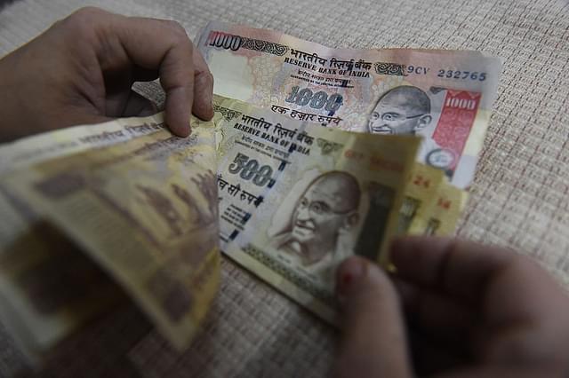 An Indian resident counts old Rs 500 and Rs 1,000 currency notes at her home. Photo credit: PRAKASH SINGH/AFP/Getty Images