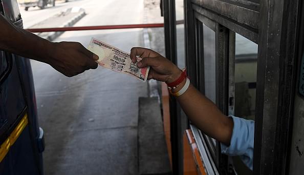 An Indian motorist pays with a 1,000 rupee note at the Nivedita Setu Toll Plaza at Rajchandrapur, on
the outskirts of Kolkata. Photo credit: DIBYANGSHU SARKAR/AFP/GettyImages.