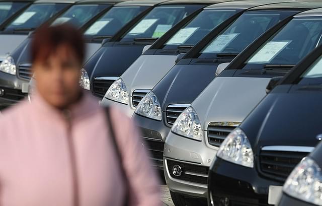 A woman walks past cars parked in a dealership. (Sean Gallup/GettyImages)