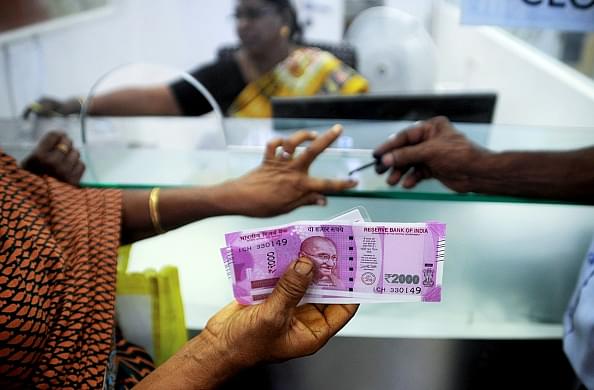 A customer displays her Rs 2,000 rupee notes as she has her finger inked with indelible ink after exchanging withdrawn 500 and 1000 rupee banknotes at a bank in Chennai. Photo credit:  ARUN SANKAR/AFP/GettyImages