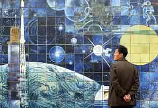 A man waits beside a space mural for a train at a Beijing subway station (FREDERIC J. BROWN/AFP/Getty Images)