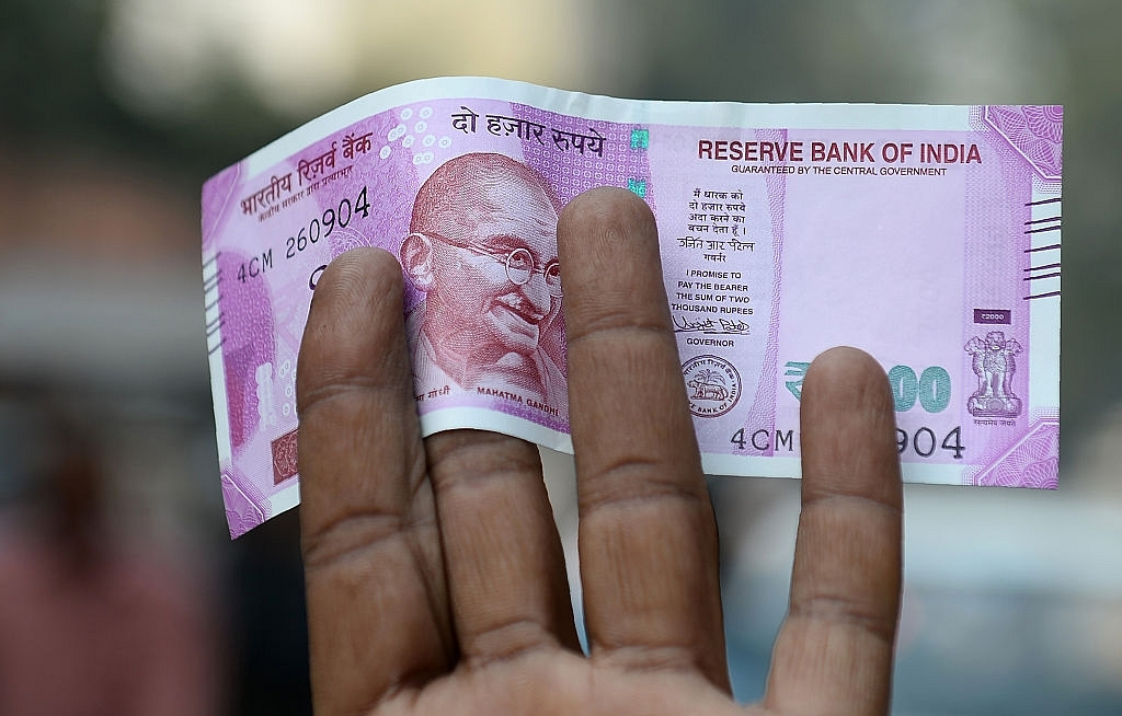 An Indian man displays a new Rs 2,000 note after exchanging his old Rs 500 and Rs 1,000 notes at a bank in New Delhi. (SAJJAD HUSSAIN/AFP/Getty Images)