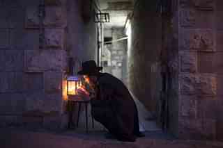 An Ultra-Orthodox Jewish man prays and lights candles on the fifth night of the Jewish holiday of Hanukkah, the festival of light, in Jerusalem, Israel. (Uriel Sinai/Getty Images)