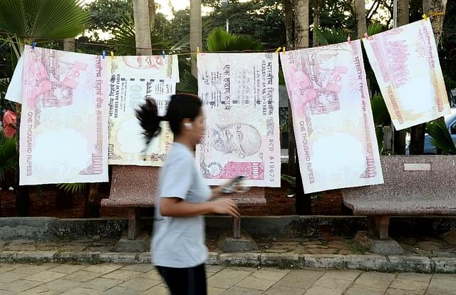 

A jogger passes replica prints of the demonetised 500 and 1000 rupee notes as part of a street art exhibition in Mumbai on November 20, 2016 (INDRANIL MUKHERJEE/AFP/Getty Images)