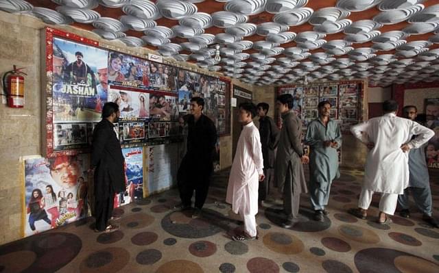 Pakistani
 cinema-goers look at photos displayed at a local cinema in Karachi, 
Pakistan. (AP Photo/Fareed Khan)

