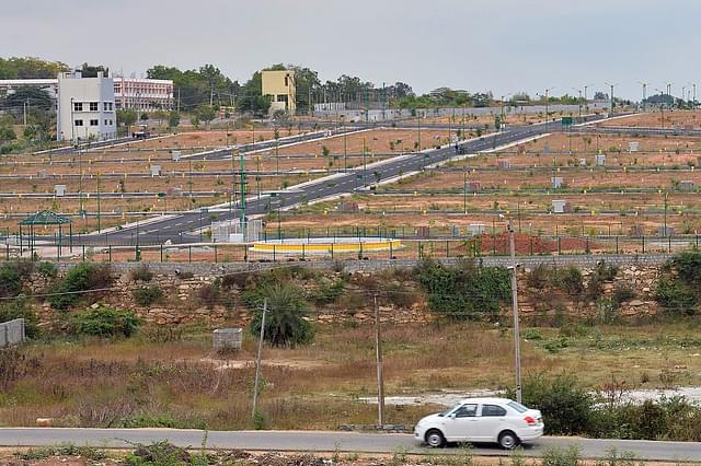 A car drives in front of residential plots on the outskirts of Bengaluru in December 2016. (MANJUNATH KIRAN/AFP/Getty Images)