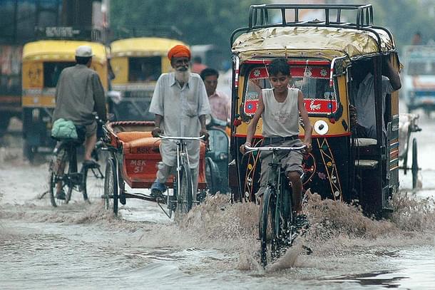 Indian commuters make their way along a waterlogged street during a heavy downpour of monsoon rain in Amritsar. (NARINDER NANU/AFP/Getty Images)