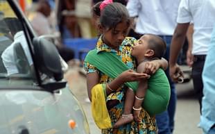 A girl carrying a toddler counts money collected by begging from commuters in Mumbai. (INDRANIL MUKHERJEE/AFP/GettyImages)