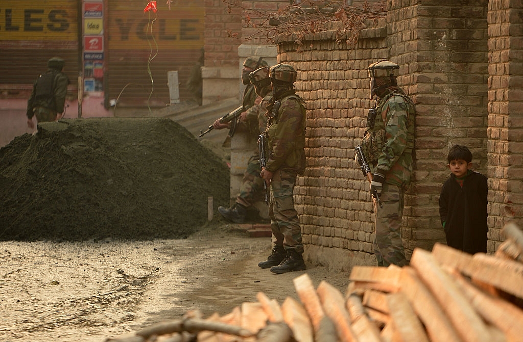 Indian army soldiers stands alert as a Kashmir boy looks on outside a house during search operations in Srinagar. (TAUSEEF MUSTAFA/AFP/Getty Images)