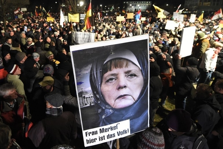 Posters showing Chancellor Angela Merkel in a Muslim headbag are appearing at every anti-Muslim invader protest


