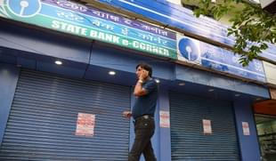 A man speaks on his cellphone as he walks past a State Bank of India branch in Siliguri. (DIPTENDU DUTTA/AFP/GettyImages)