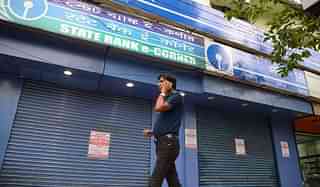 

A man speaks on his cellphone as he walks past a State Bank of India branch in Siliguri. (DIPTENDU DUTTA/AFP/GettyImages)
