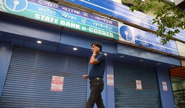 A man speaks on his cellphone as he walks past a State Bank of India branch in Siliguri. (DIPTENDU DUTTA/AFP/GettyImages)