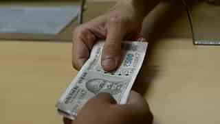 

A bank staff member hands Indian 500 rupee notes to a customer. (INDRANIL MUKHERJEE/AFP/GettyImages)