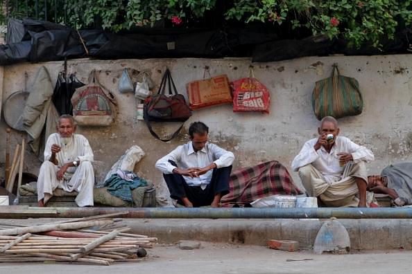 Men sit on a pavement next to their beds in  Delhi, India. (Dan Istitene/GettyImages)