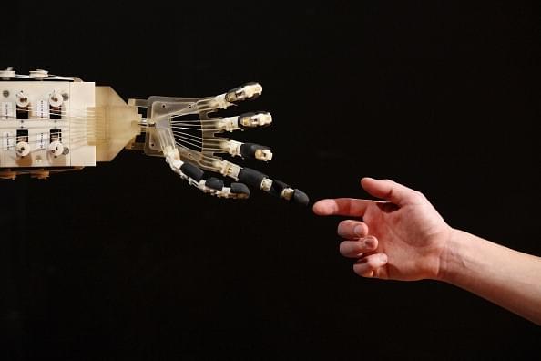 Robotics student Gildo Andreoni interacts with a Dexmart robotic hand built at the University of Bologna in the Robotville exhibition in London, England. (Oli Scarff/Getty Images)