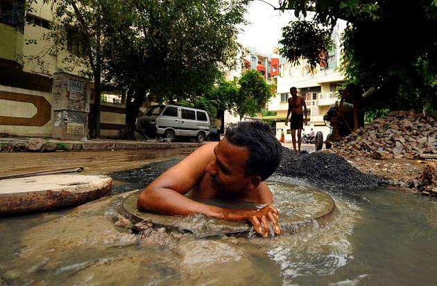 A person engaging in manual scavenging work without protective gear (Dalit Network/Wikimedia Commons)