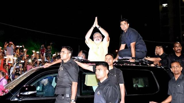 Prime Minister Modi gestures to his supporters during the road show in Surat on Sunday. (PTI)&nbsp;