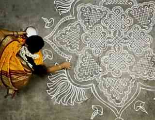 A woman draws a kolam (rangoli) for the New Year