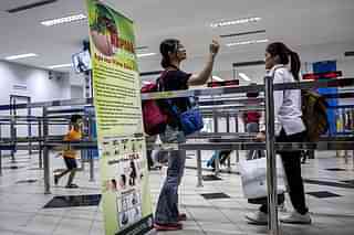 Ferry passengers arriving from Singapore walk near a banner about Zika virus at the International Ferry Terminal Batam Centre in Indonesia.&nbsp;