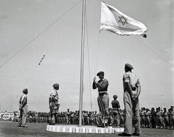 The flag of the future Jewish State is raised at morning parade at an IDF training base in 1948 in what was still the British Mandate for Palestine. (Zoltan Kluger/GPO via Getty Images)