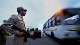 A security person stands guard as pilgrims leave for the Amarnath Yatra