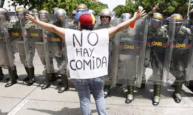 
A woman with a sign reading ‘There is no food’ protests against new emergency powers decreed by President Nicolás Maduro.


