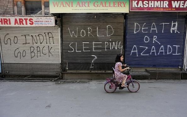 A Kashmiri girl rides bicycle in front of closed shops during restrictions in Srinagar. (Waseem Andrabi/Hindustan Times via GettyImages)
