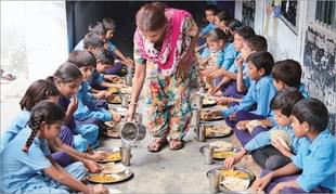 A caretaker serves mid-day meal to the students