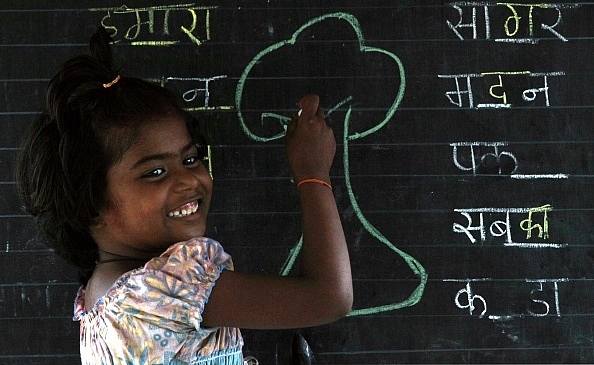 Street Child Laxmi a student of ‘school on wheels’ maintained by ‘DoorStep School’ tries to learn hindi on World Literacy Day at Fashion Street in Mumbai. (Anshuman Poyrekar/Hindustan Times via Getty Images)