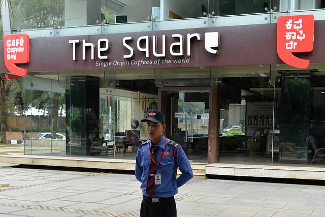 A guard watches a CCD outlet as IT Raids were conducted (MANJUNATH KIRAN/AFP/Getty Images)