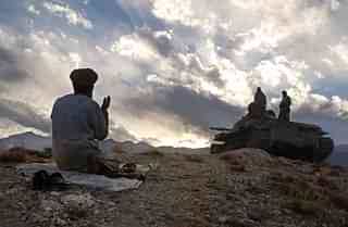 An anti-Taliban soldier 
prays near a tank on the hills overlooking the Tora 
Bora. (Photo by Chris Hondros/Getty Images)


