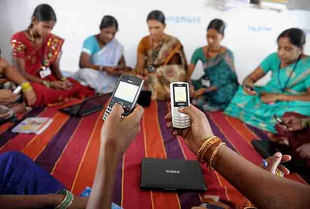 Indian villagers, part of a Self Help Group (SHG) organisation, pose with mobile phones and laptops in Bibinagar village outskirts of Hyderabad on March 7, 2013, on the eve of International Women’s day. (NOAH SEELAM/AFP/Getty Images)