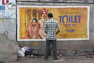 An Indian man urinates on a wall on the roadside in front of a poster for the Hindi film ‘Toilet’ in Hyderabad on August 12, 2017. The Bollywood film ‘Toilet: Ek Prem Katha’ (‘Toilet: A love story’), which was released on August 11, is inspired by the true-life tale of one man’s battle to build toilets in his village in rural India. / AFP PHOTO / NOAH SEELAM (Photo credit should read NOAH SEELAM/AFP/Getty Images)