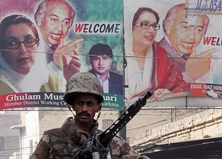 A Pakistani paramilitary soldier stands guard next to posters of slain former Pakistani premier Benazir Bhutto and her father Zulfiqar Ali Bhutto in Larkana. (AAMIR QURESHI/AFP/Getty Images)
