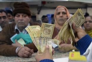 An Indian bank teller counts out notes as citizens gather inside a bank to deposit and exchange old Rs 500 and Rs 1,000 notes. (NARINDER NANU/AFP/Getty Images)
