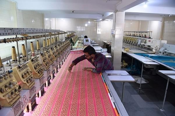 An Indian textile maker works on an embroidery machine at a workshop. (SAM PANTHAKY/AFP/Getty Images)