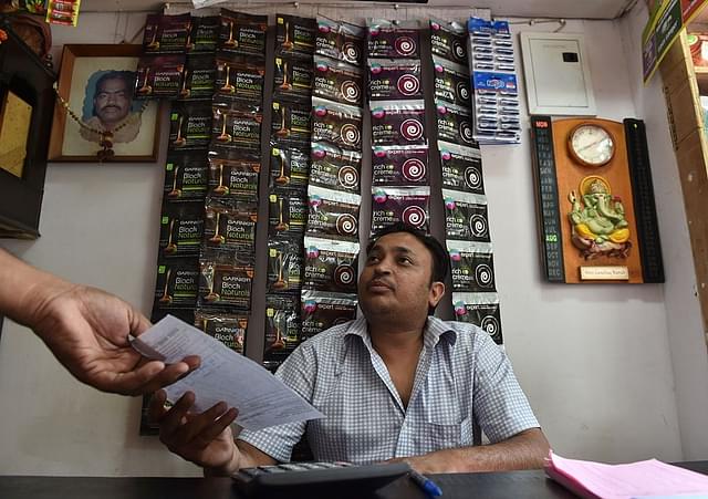 An Indian shopkeeper hands a bill to a customer at his shop in New Delhi. (SAJJAD HUSSAIN/AFP/GettyImages)