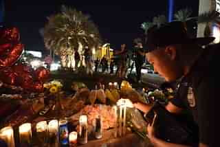 Edrian Pateno of Corona, California lights candles at a makeshift memorial near the Mandalay Hotel on the Las Vegas Strip on 3 October, after a gunman killed 59 people and wounded more than 500 others, before taking his own life, when he opened fire from a hotel on a country music festival.&nbsp; (Robyn Beck/AFP/GettyImages)