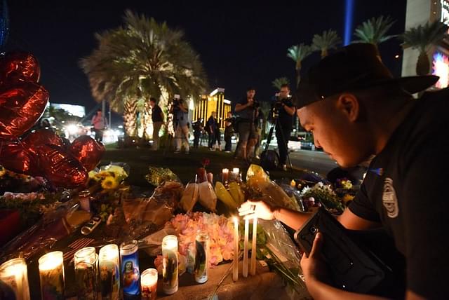 Edrian Pateno of Corona, California lights candles at a makeshift memorial near the Mandalay Hotel on the Las Vegas Strip on 3 October, after a gunman killed 59 people and wounded more than 500 others, before taking his own life, when he opened fire from a hotel on a country music festival.&nbsp; (Robyn Beck/AFP/GettyImages)