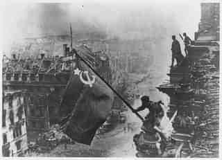 Russian soldiers flying the Red Flag, made from table cloths, over the ruins of the Reichstag in Berlin. (Yevgeny Khaldei/Getty Images)
