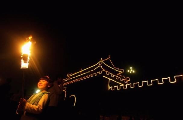 A girl holds a torch during an event to mark the Mid-Autumn Festival beside an ancient city wall in 2006 in Shouxian County of Anhui Province, China. (China Photos/Getty Images)