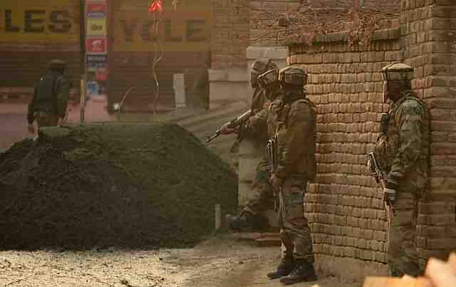 Indian army soldiers stands alert as a Kashmir boy looks on outside a house during search operations in Srinagar.(Representative Image)  (TAUSEEF MUSTAFA/AFP/Getty Images)