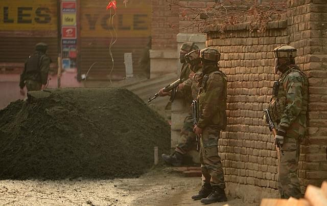 Indian army soldiers stands alert as a Kashmir boy looks on outside a house during search operations in Srinagar. (TAUSEEF MUSTAFA/AFP/Getty Images)