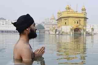 A Sikh devotee takes bath in the holy sarovar and pays obeisance at Golden Temple in Amritsar. (Sameer Sehgal/Hindustan Times via Getty Images)
