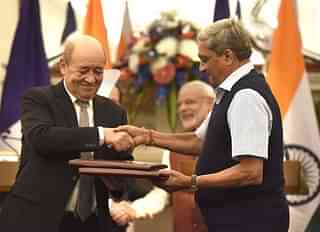 Former defence minister Manohar Parrikar and his French counterpart Jean-Yves Le Drian exchange the files of agreements on the buying of Rafale fighter jets. (Arvind Yadav/Hindustan Times via Getty Images)