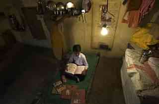 A boy studies under an electric lightbulb in Haryana (Priyanka Parashar/Mint via Getty Images)