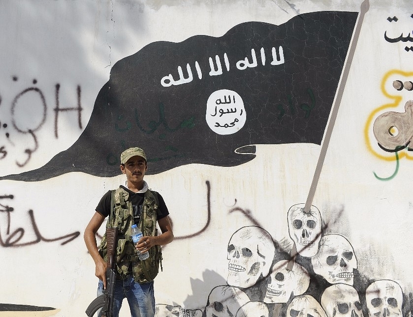 An Iraqi security force member stands in the backdrop of a Islamic State mural. (Defne Karadeniz via Getty Images)