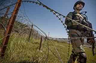 An Indian Army soldier patrols the fence near LoC  (Gurinder Osan/Hindustan Times via Getty Images)