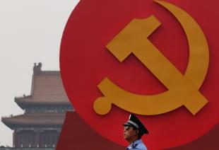 A policeman patrols under a giant communist emblem on the Tiananmen Square.(Photo by Feng Li/Getty Images)